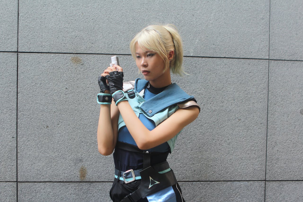 home-hero-2 Cosplayer dressed in a futuristic outfit poses against a gray wall outdoors, exuding a sci-fi style.